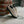 Beige  Herman 3 sneakers with black soles leaning against a brick wall.