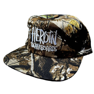 Camouflage cap with 'Heroin Skateboards' text on a white background