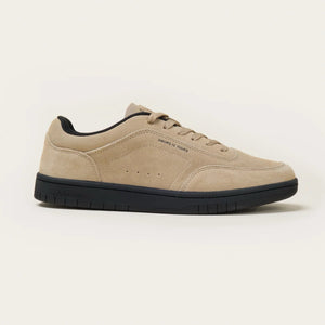 Beige sneaker with black sole on a light beige background