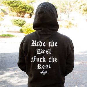 Person wearing a black warping Motörhead  hoodie with text on the back, standing outdoors.