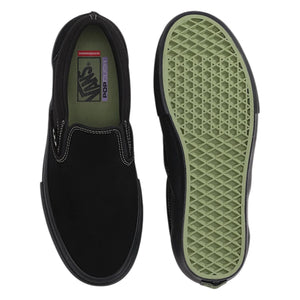 A pair of black olive skate slip-on sneakers shown from the top and side, with the textured light green outsole visible on the right. Theskate  Vans checkered logo is visible on the inner label.